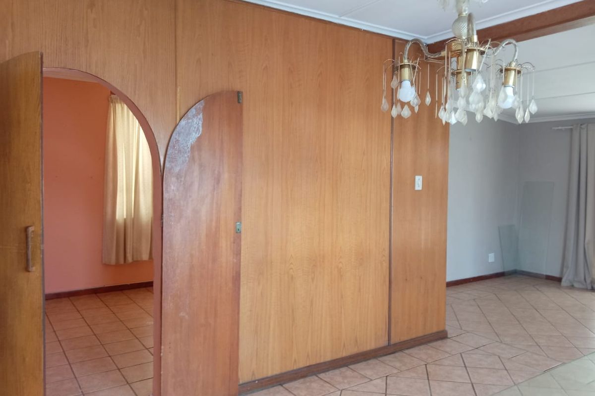 Interior view of a living area featuring wood-paneled walls, tiled flooring, and an arched doorway leading to an adjacent room.