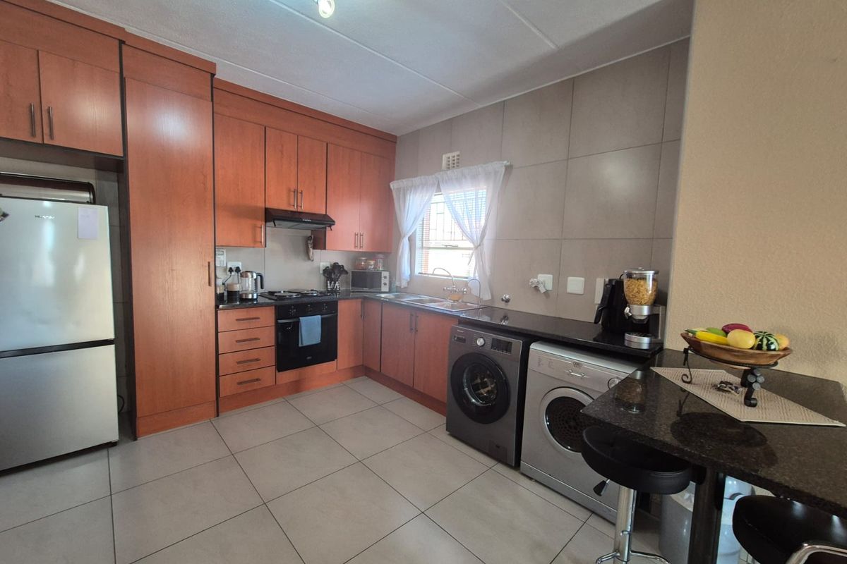 A functional kitchen featuring wood-finish cabinetry, granite countertops, a built-in oven and hob, and integrated space for laundry appliances.