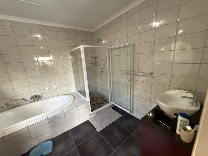 A functional bathroom featuring a built-in bathtub, a separate glass-enclosed shower, and a modern vessel sink vanity with tiled walls and flooring.
