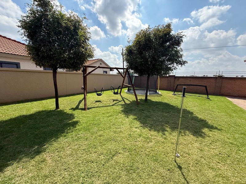 A well-maintained private rear garden featuring a level lawn, perimeter boundary walls, and established trees.