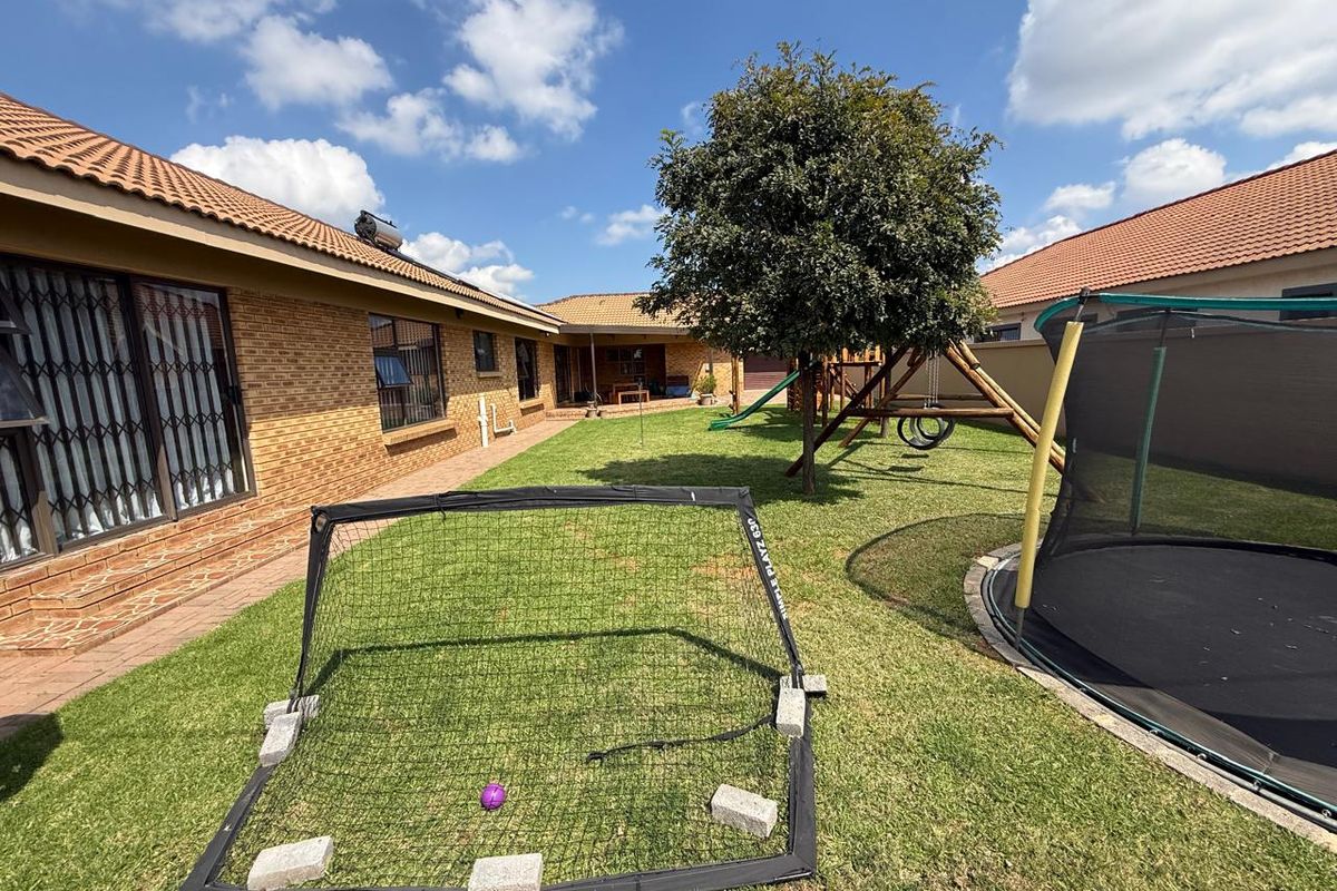 A spacious rear garden area featuring a well-maintained lawn, brick exterior walls, and a tiled roof, providing a private outdoor space.