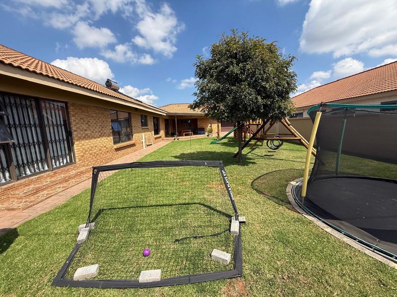 A spacious rear garden area featuring a well-maintained lawn, brick exterior walls, and a tiled roof, providing a private outdoor space.