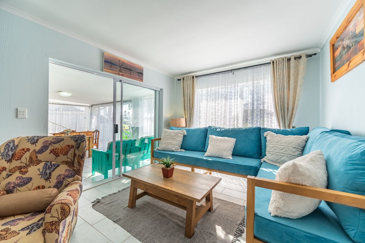 A bright living room featuring tiled flooring and large sliding glass doors that provide seamless access to an enclosed patio area.
