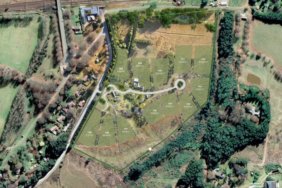 Aerial view of a residential land development showing multiple subdivided plots with established access roads and surrounding natural landscape.