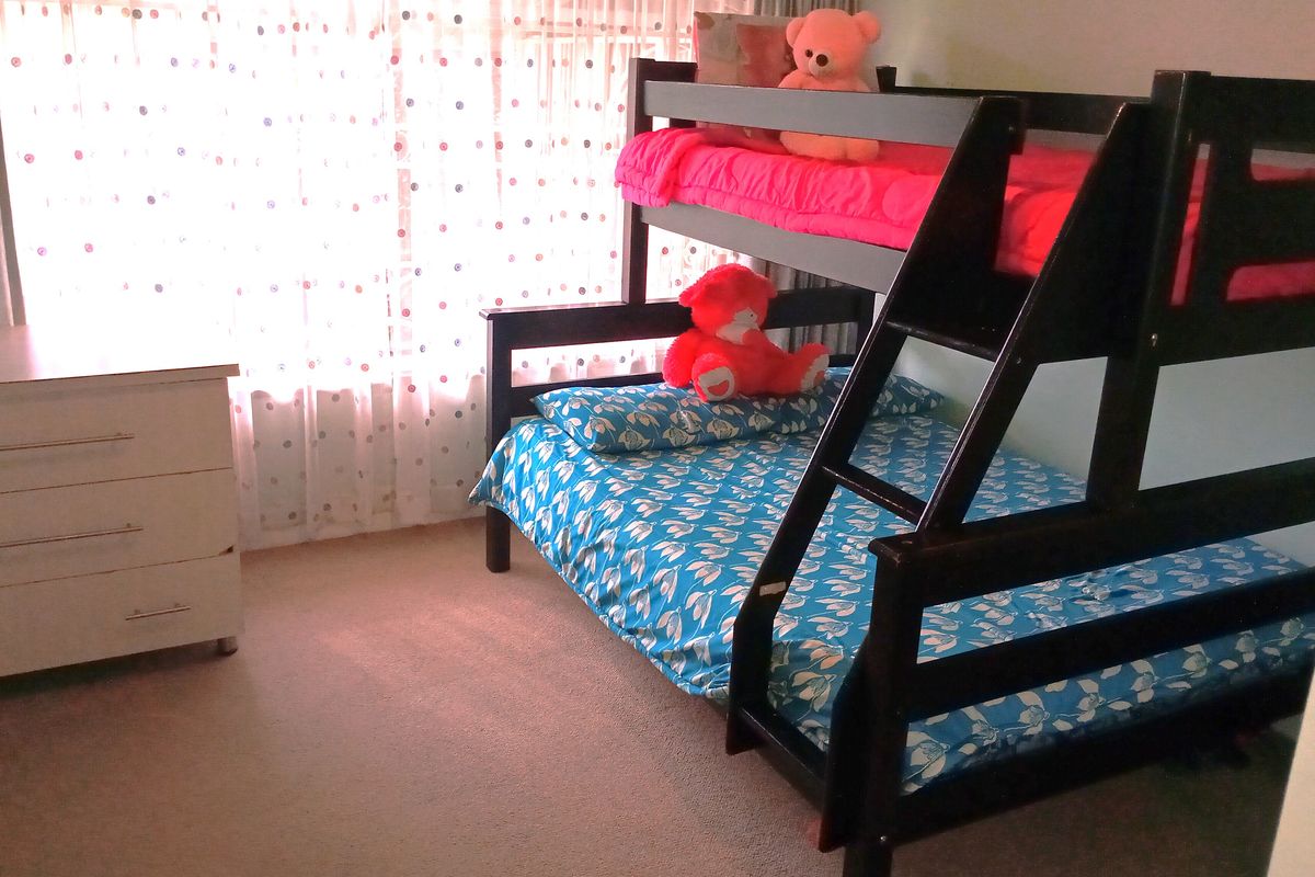 A bedroom featuring carpeted flooring and a large window with curtains, providing natural light to the space.
