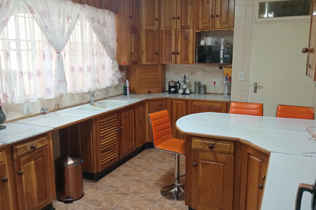 A traditional kitchen featuring solid wood cabinetry, a breakfast bar, tiled flooring, and a double-basin sink with a window view.