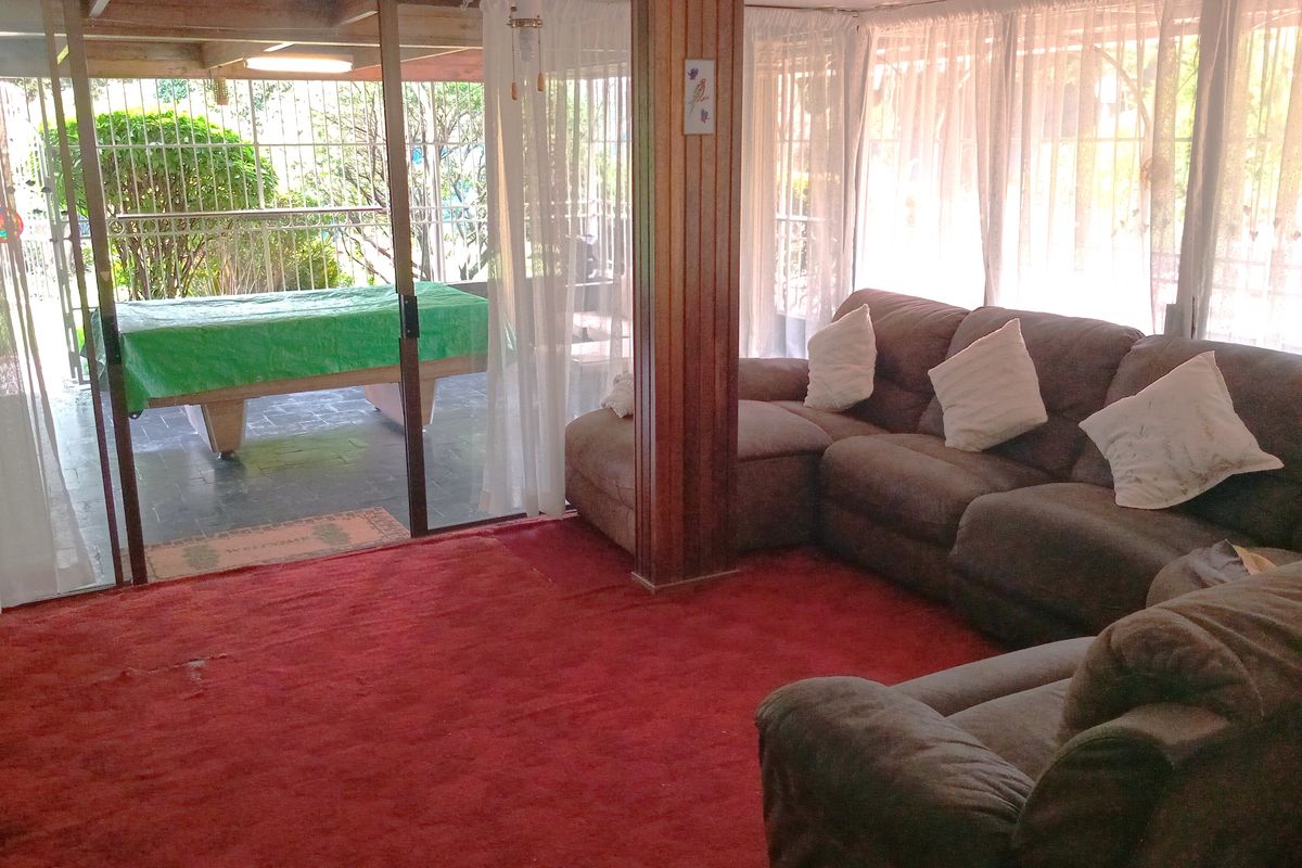 A living room featuring wood paneling and large sliding glass doors that open onto a covered patio area.