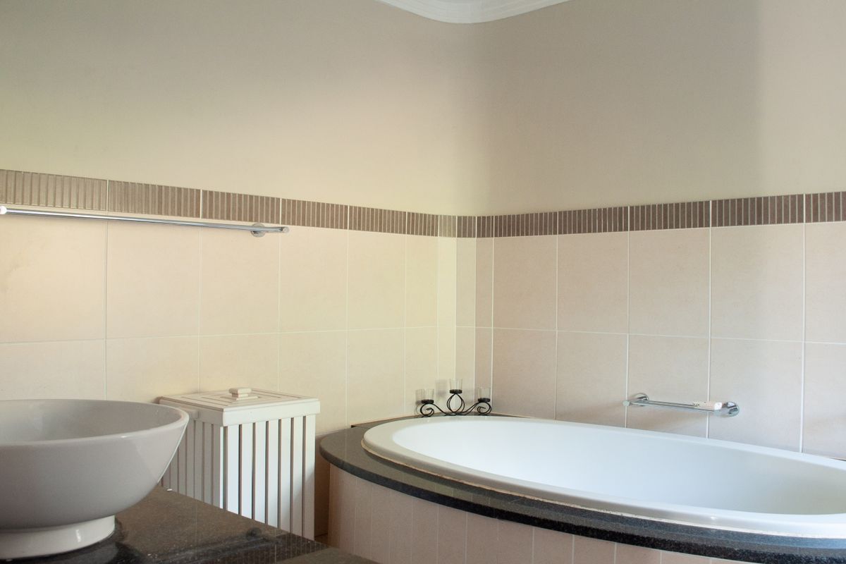 A well-maintained bathroom featuring a built-in oval bathtub with granite surround and a modern vessel sink vanity.