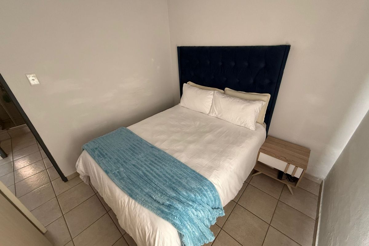 A compact bedroom featuring neutral wall finishes and tiled flooring, providing a functional space for rest.