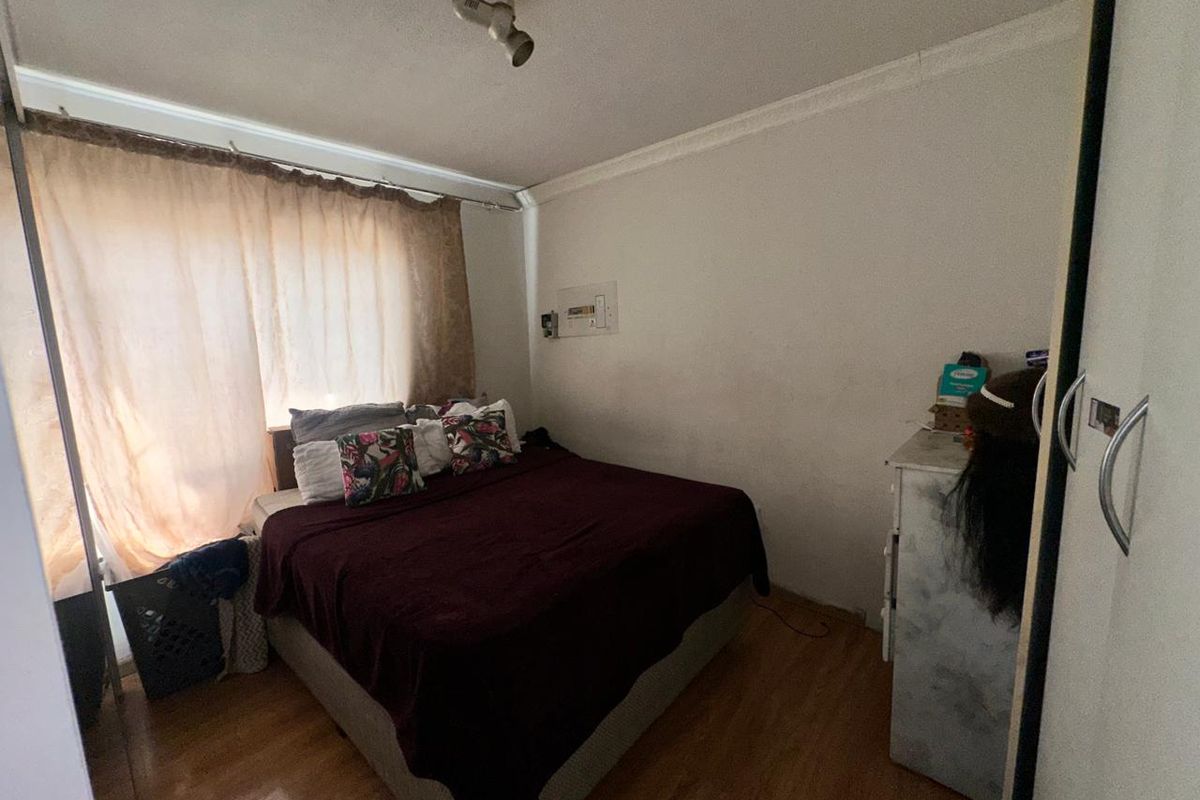 A bedroom featuring laminate flooring, coving, and a built-in wardrobe. The space requires cosmetic updates to the wall finishes.