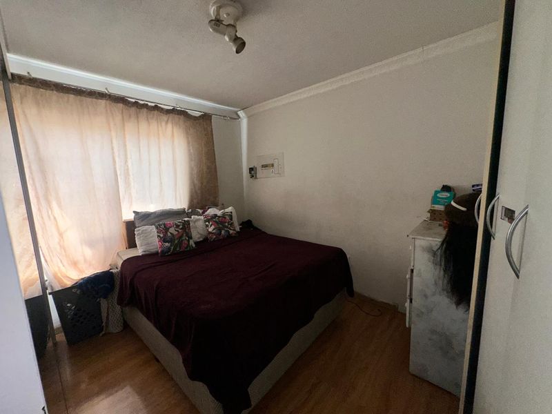 A bedroom featuring laminate flooring, coving, and a built-in wardrobe. The space requires cosmetic updates to the wall finishes.