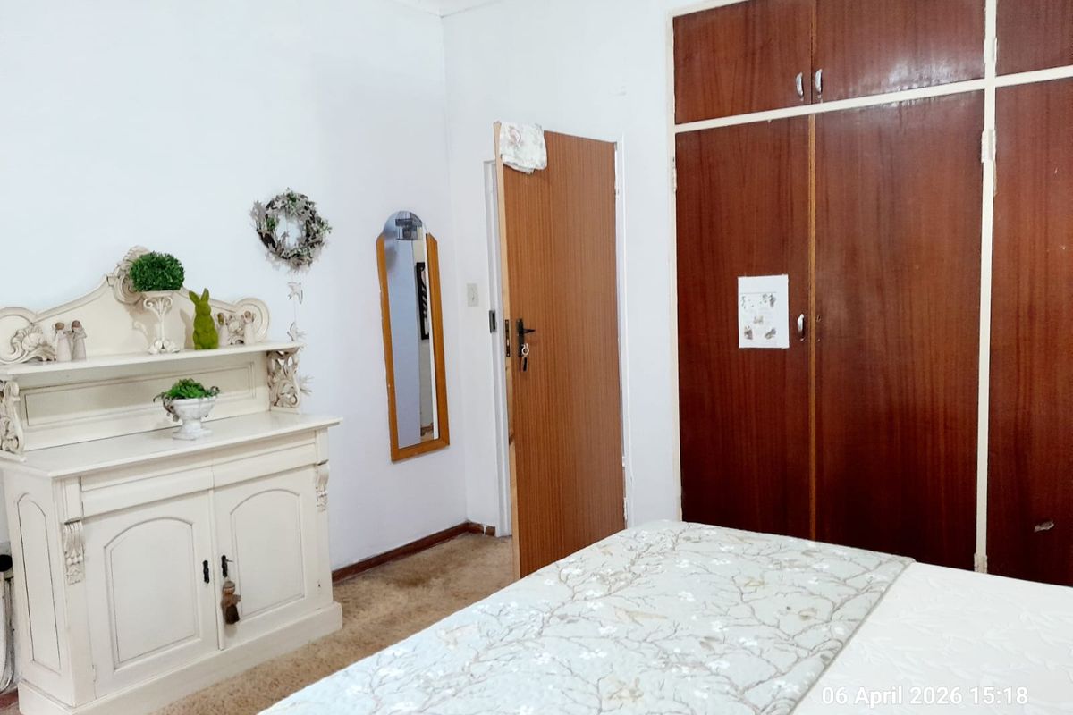 A bedroom featuring built-in wooden cupboards and carpeted flooring, offering a functional space with traditional finishes.