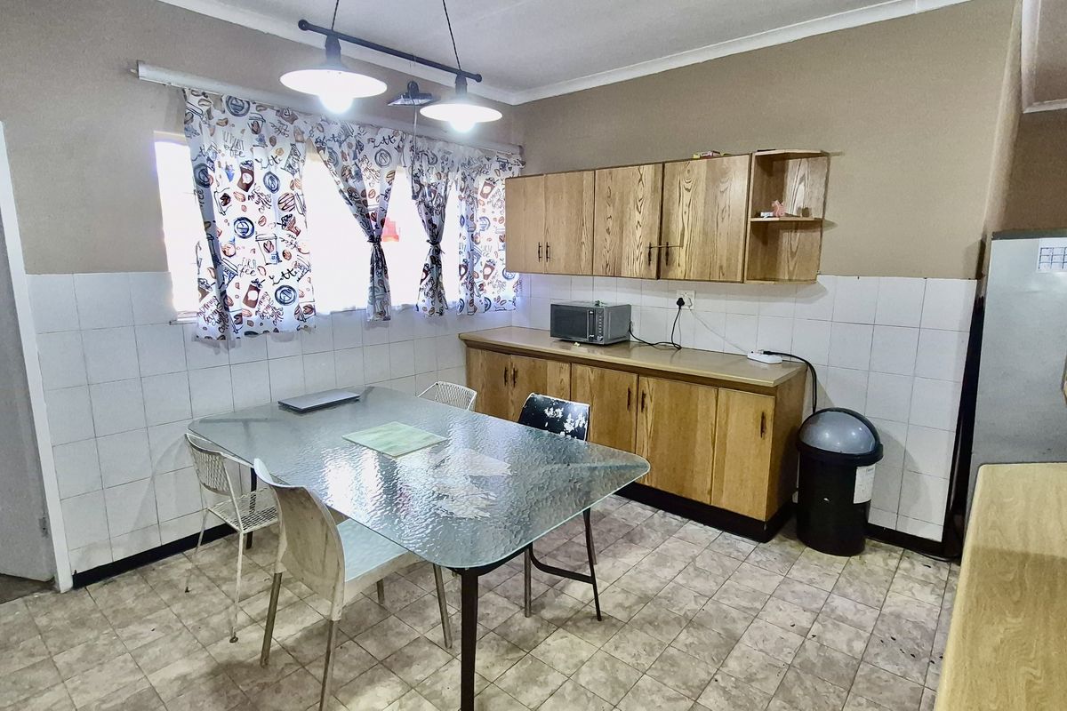 A functional kitchen featuring wooden cabinetry, tiled splashbacks, and tiled flooring, providing a practical space for meal preparation and dining.