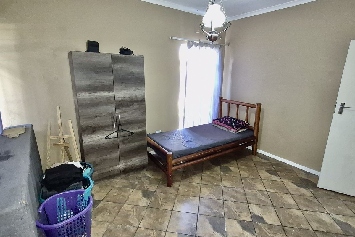 A functional bedroom featuring tiled flooring, a standard door, and a central light fixture, providing a simple and practical living space.