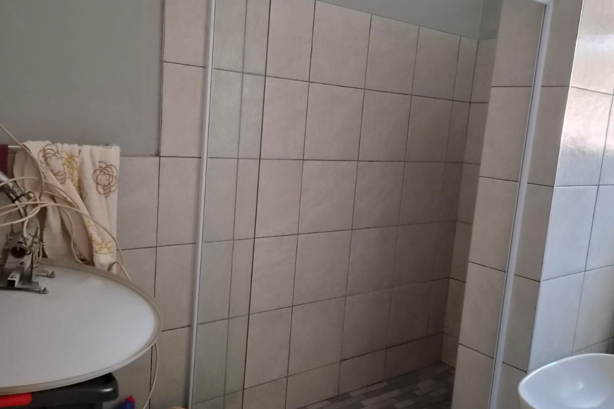 A bathroom featuring a walk-in shower enclosure with tiled walls and flooring, alongside a vanity basin.