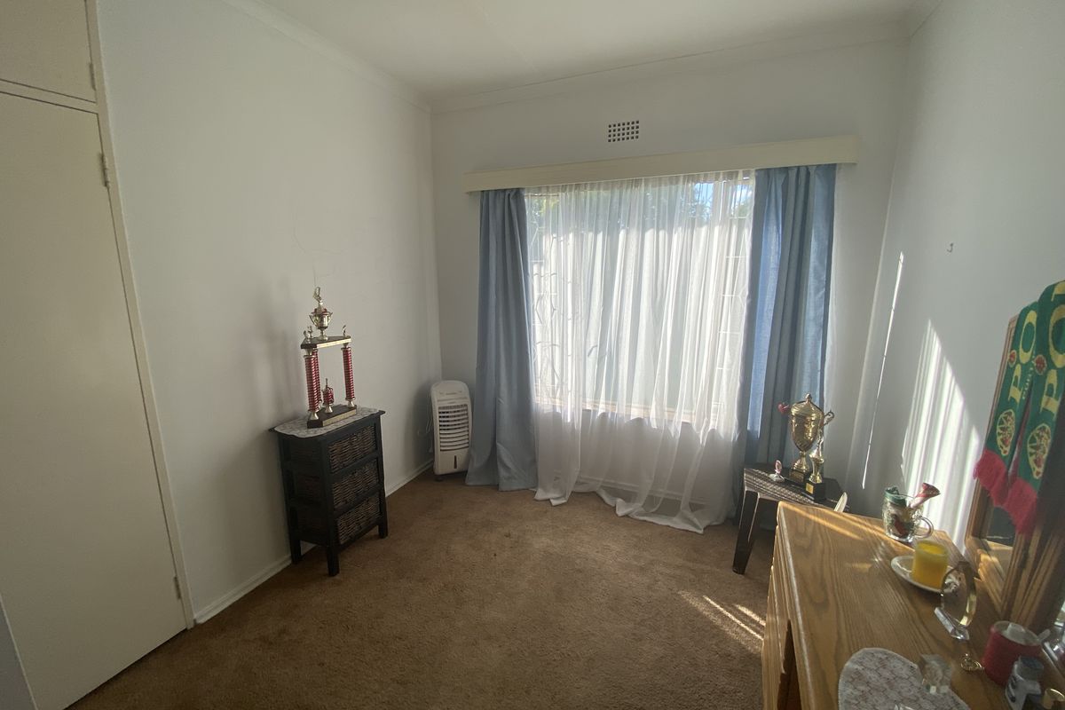 A bedroom featuring built-in cupboards, carpeted flooring, and a large window with natural light.