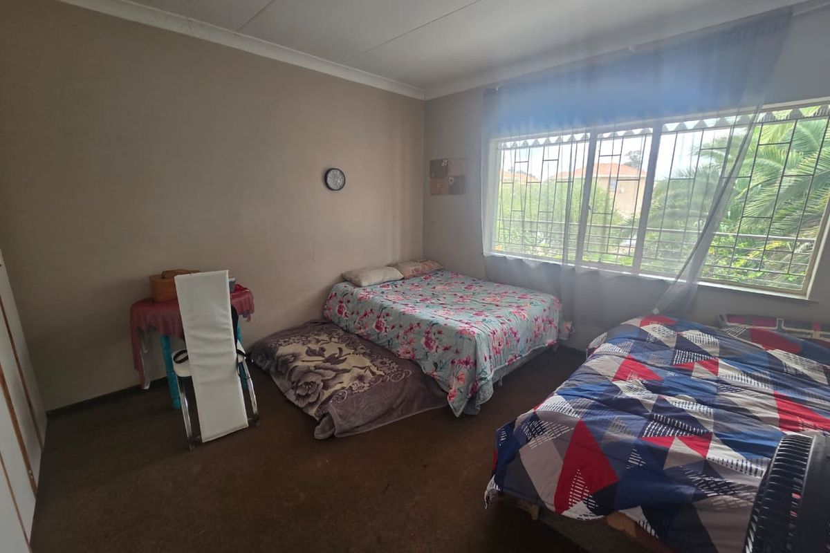 A bedroom featuring large windows with security bars, carpeted flooring, and coved ceiling finishes.
