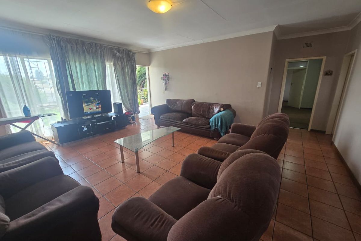 Spacious living room featuring terracotta floor tiles, large windows with natural light, and direct access to an outdoor balcony area.