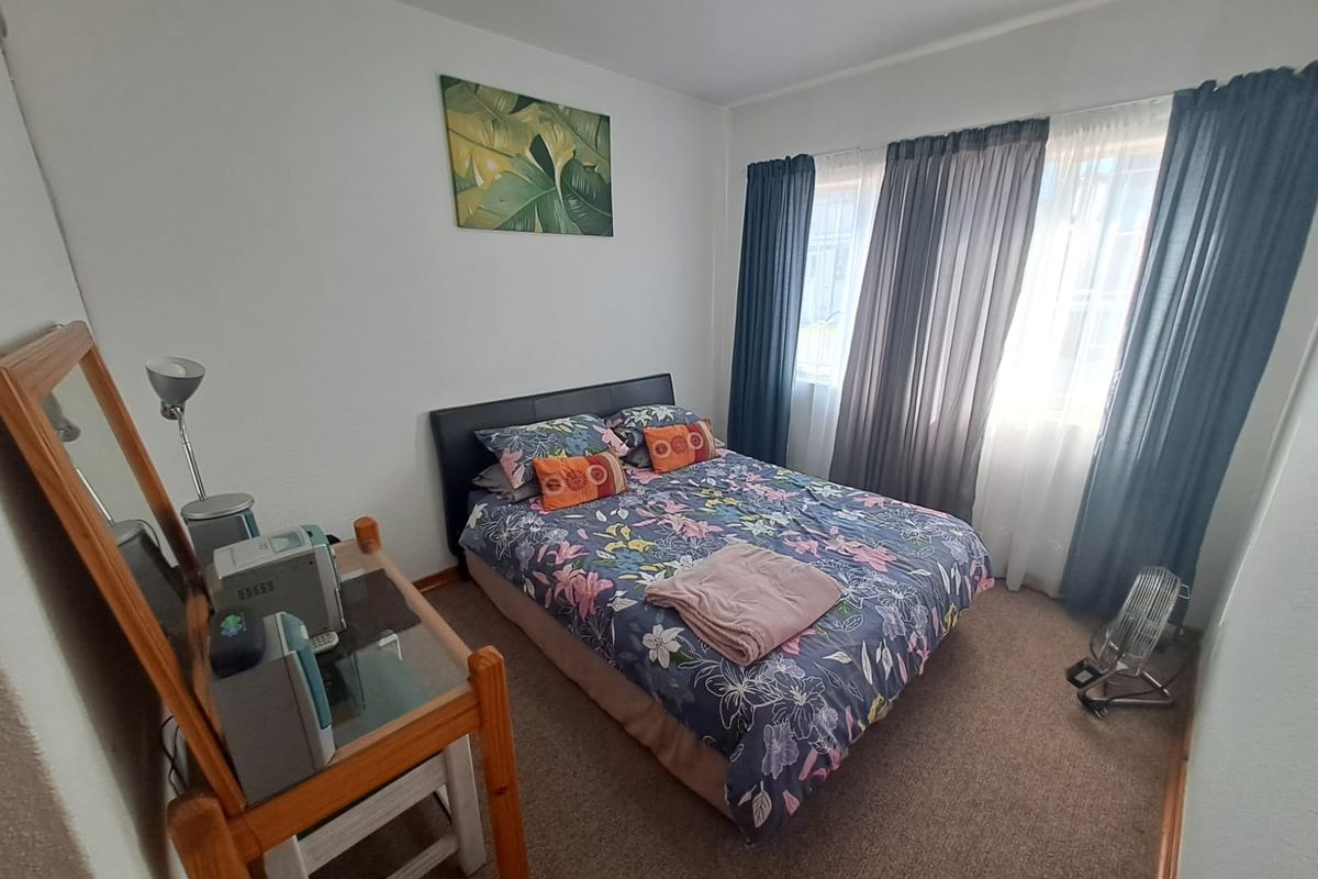 A functional bedroom featuring carpeted flooring and large windows with curtain tracks, providing natural light and a comfortable living space.