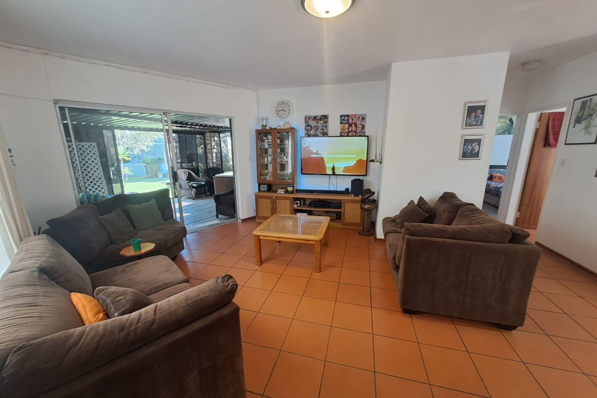 Spacious living room featuring terracotta floor tiles and large sliding glass doors providing direct access to the outdoor patio area.