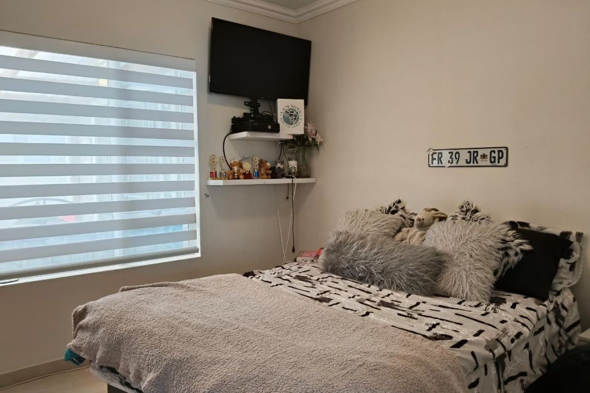 A well-maintained bedroom featuring modern zebra blinds and neutral wall finishes, providing a comfortable and functional living space.