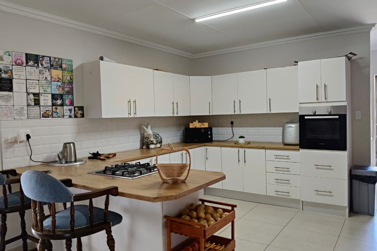 Modern kitchen featuring white cabinetry, wood-look countertops, a built-in oven, and a gas hob integrated into the breakfast bar island.
