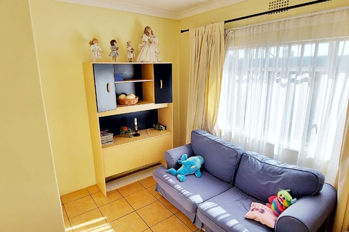 A cozy living room featuring tiled flooring, a large window with curtain tracks, and neutral wall finishes.