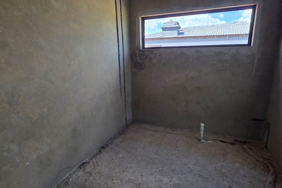 An unfinished bathroom space in shell condition, featuring exposed plaster walls, concrete flooring, and plumbing rough-ins ready for final fixtures and finishes.