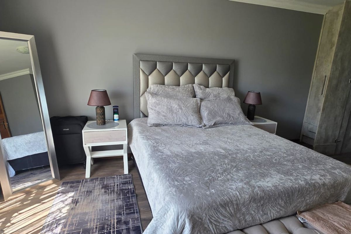 A well-maintained bedroom featuring laminate flooring, neutral grey walls, and a built-in wardrobe with ample storage space.