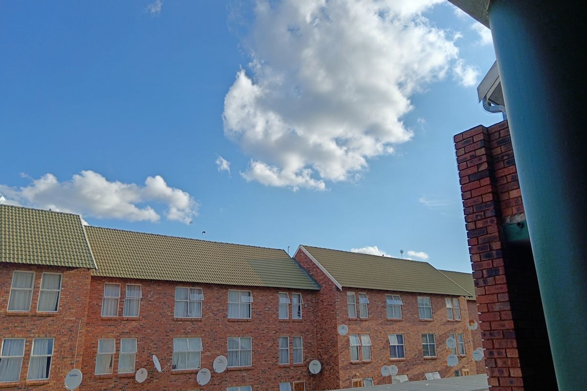 View of the apartment complex exterior featuring face brick facade, tiled roofing, and covered parking bays.