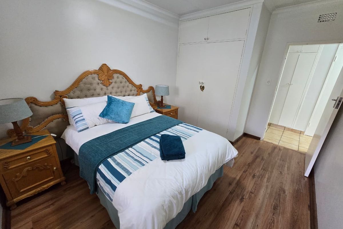 A bedroom featuring wood-look flooring, built-in cupboards, and crown molding, providing a functional and well-maintained living space.