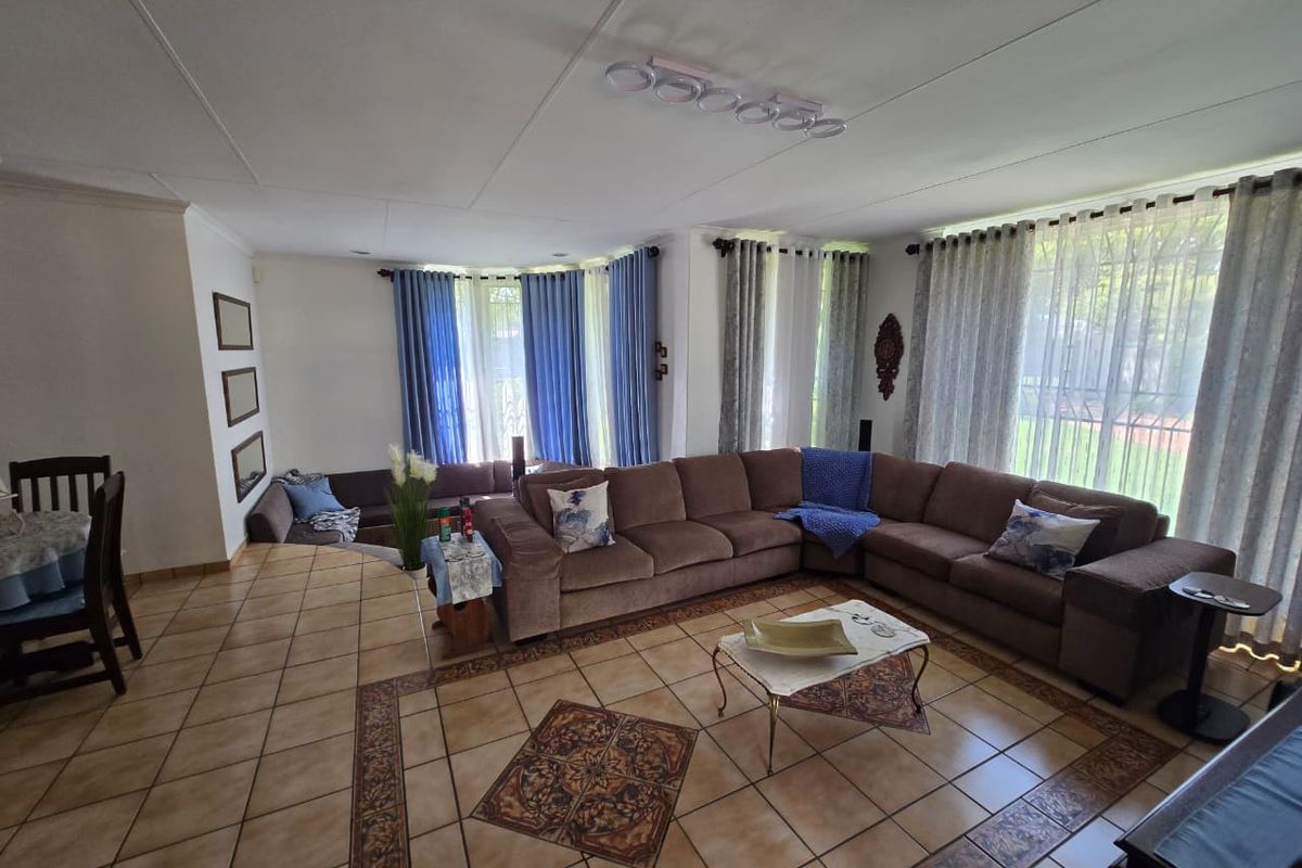 Spacious living area featuring large windows with natural light, tiled flooring with decorative inlay, and a sunken lounge section.