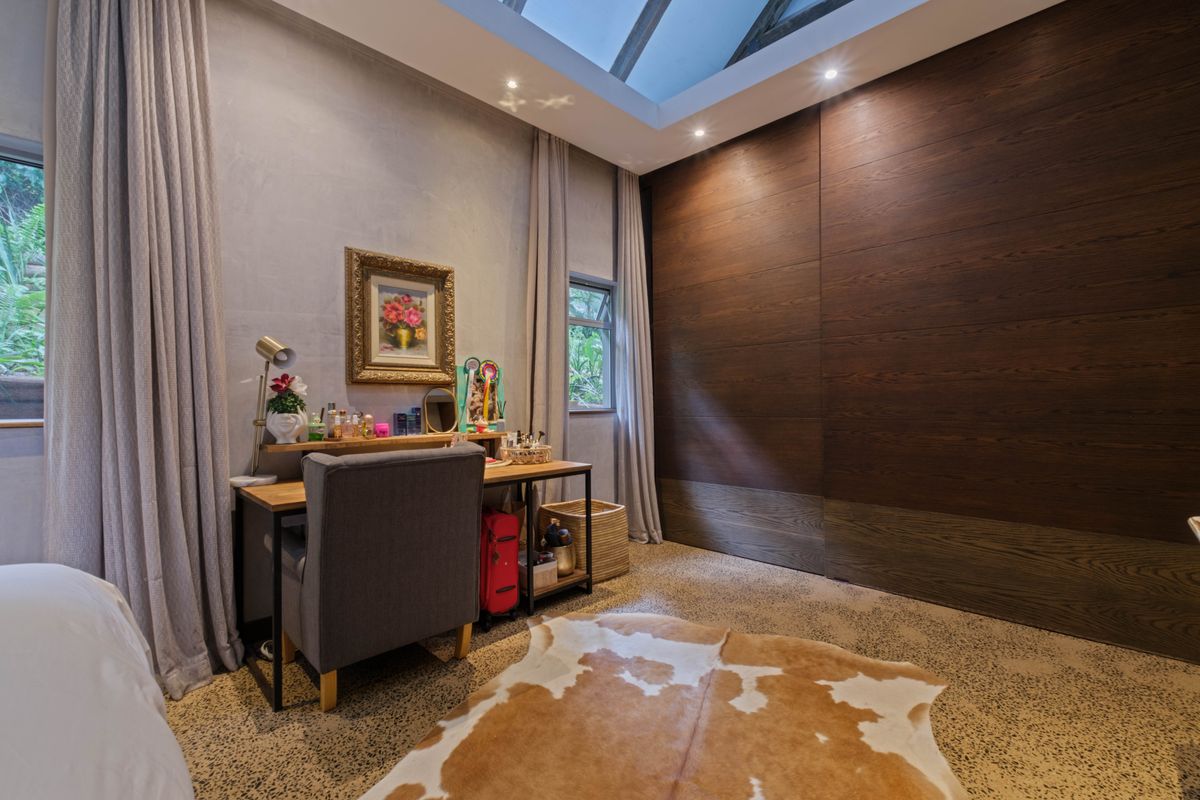 A well-appointed bedroom featuring a large skylight, polished concrete flooring, and extensive dark wood built-in cabinetry.