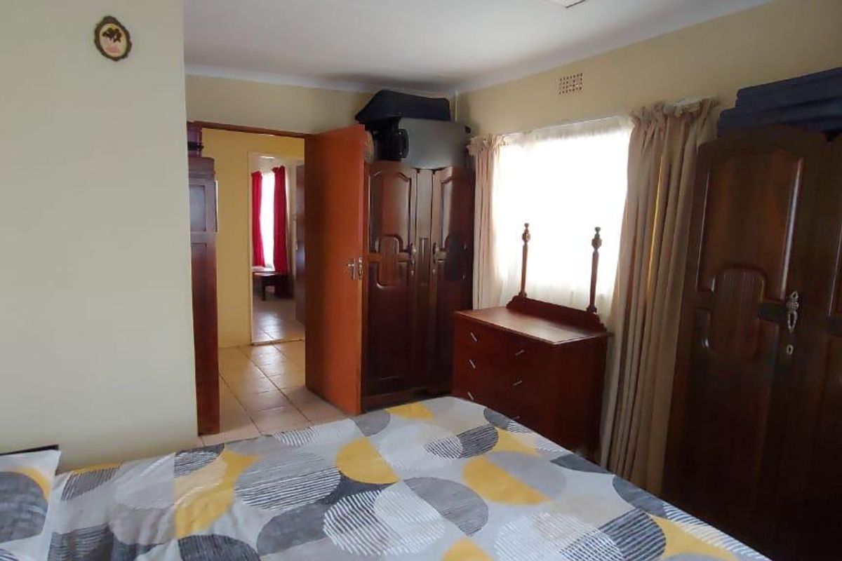 A bedroom featuring neutral wall tones, a window with curtains, and tiled flooring, providing a functional living space.