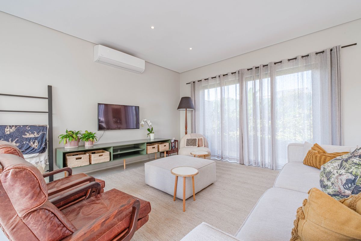 A bright and well-maintained living room featuring recessed lighting, a wall-mounted air conditioning unit, and large sliding glass doors leading to the outdoors.