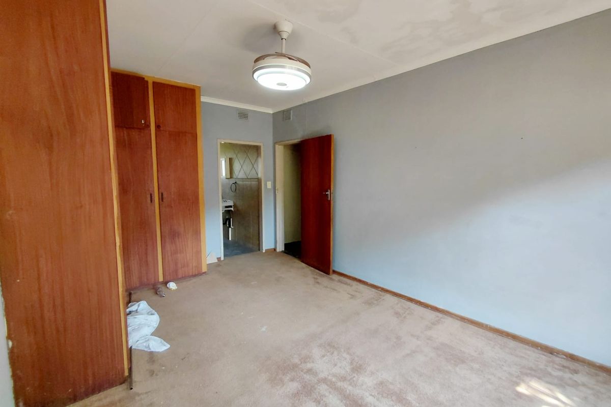 A bedroom featuring built-in wooden cupboards, carpeted flooring, and direct access to an adjacent bathroom.