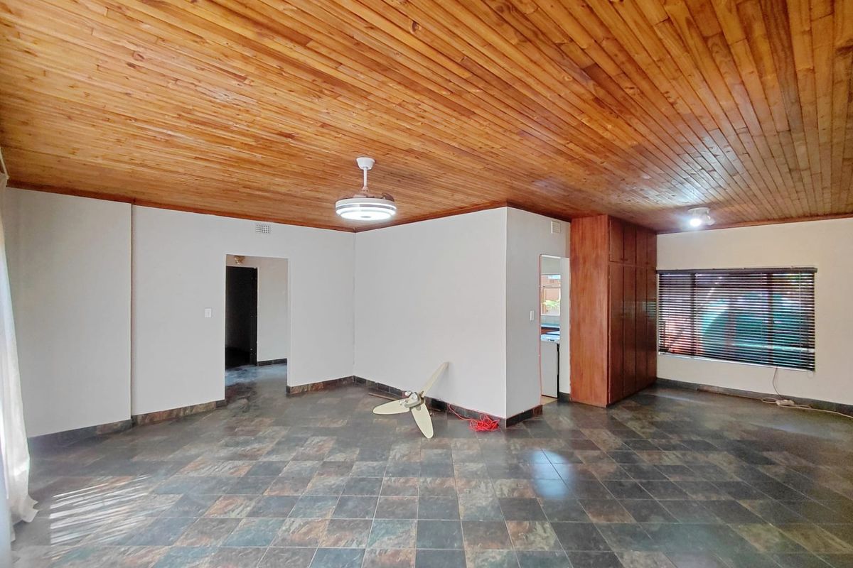 Spacious living area featuring a distinctive timber-clad ceiling, tiled flooring, and built-in storage cabinetry.