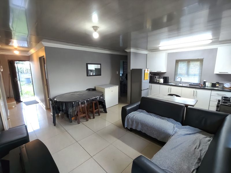 Open-plan living and kitchen area featuring tiled flooring, modern white cabinetry, and direct access to the exterior.