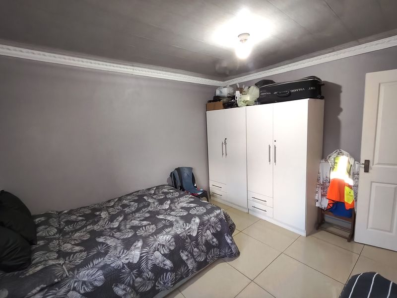 A bedroom featuring tiled flooring, a built-in wardrobe, and decorative ceiling cornicing.