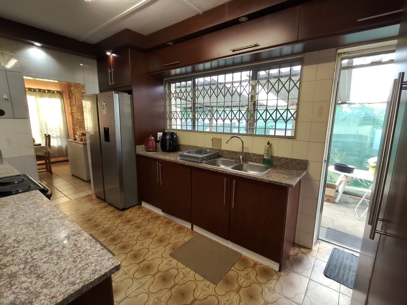 A functional kitchen featuring dark wood-look cabinetry, granite-style countertops, a double sink, and direct access to an outdoor area.