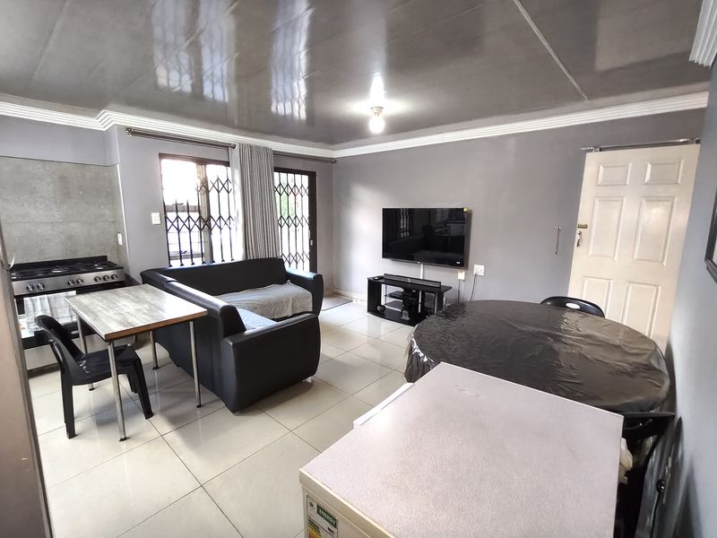 Open-plan living and kitchen area featuring tiled flooring, coved ceilings, and integrated stove, providing a functional and versatile living space.