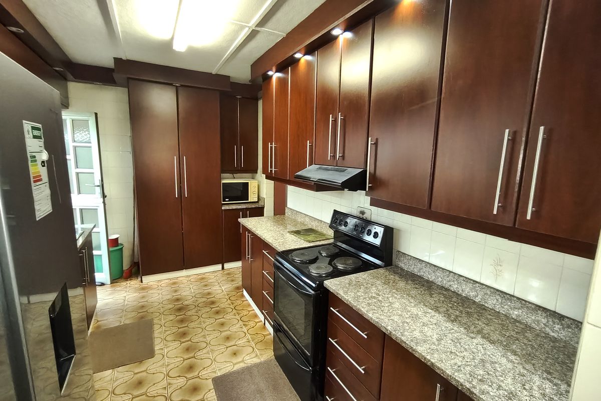 A functional kitchen featuring dark wood cabinetry, granite countertops, and an electric stove with an integrated extractor fan.