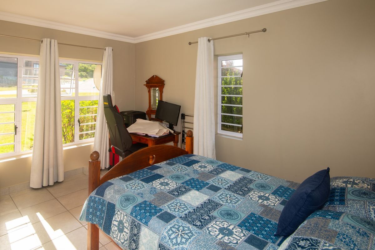 A bright bedroom featuring tiled flooring, large windows with natural light, and neutral wall finishes.