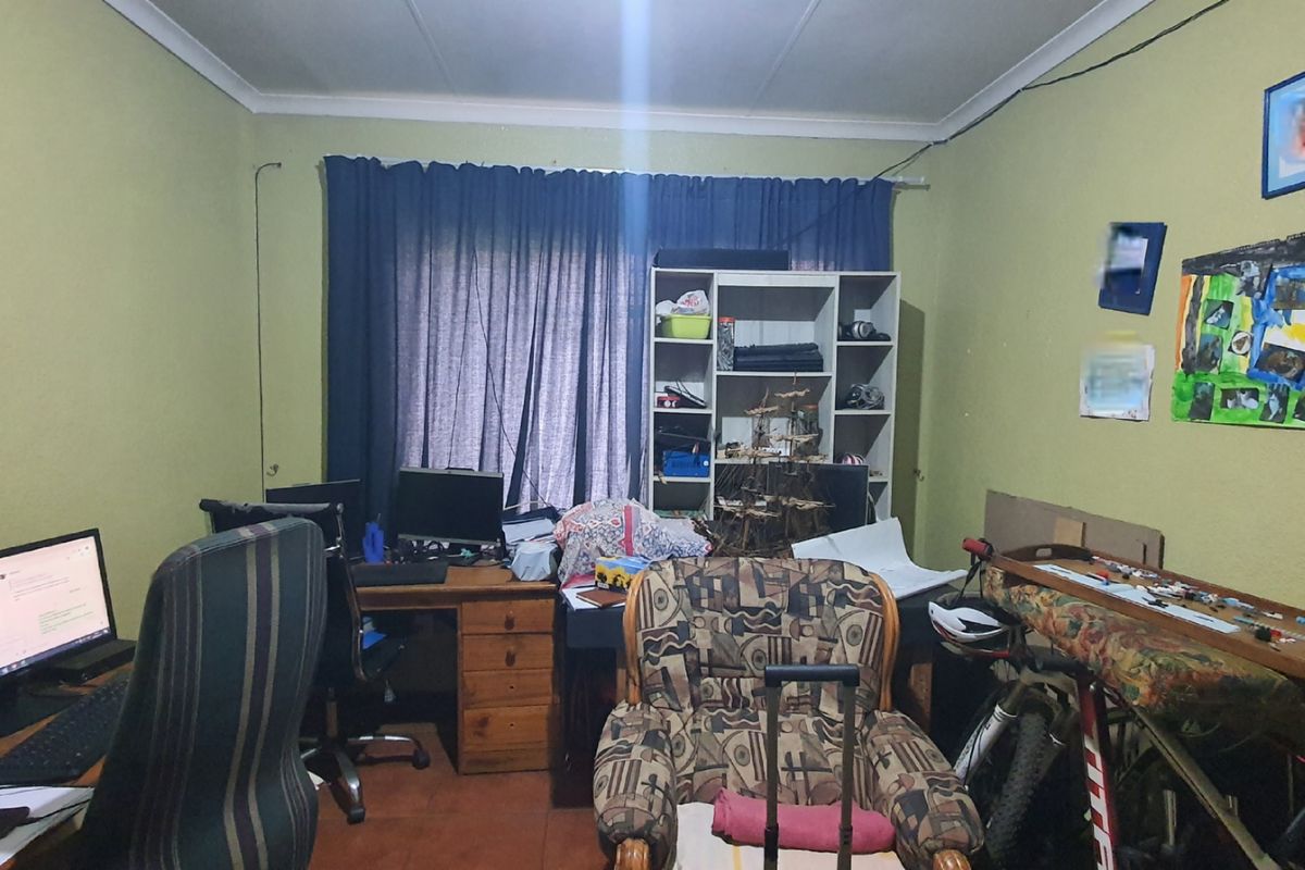 A functional bedroom or home office space featuring tiled flooring and standard window treatments, suitable for a variety of uses.