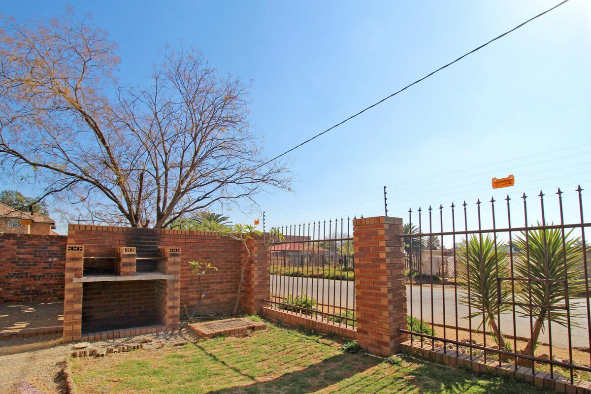 Outdoor area featuring a built-in brick braai, enclosed by a perimeter brick wall and metal security fencing with electric wiring.