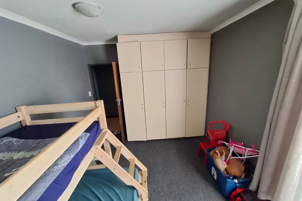 A bedroom featuring built-in cupboards and grey carpeting, providing functional storage space.