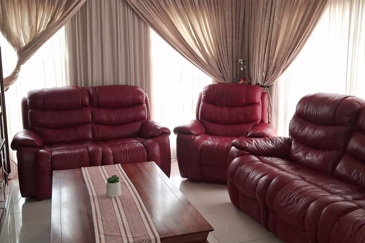 A bright living room featuring large windows with floor-to-ceiling curtains and neutral tiled flooring.