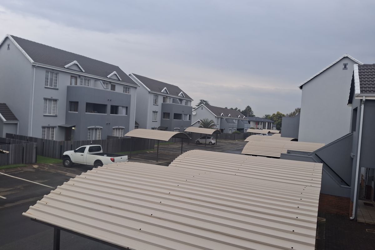 Elevated view of the apartment complex grounds, featuring multiple covered parking carports and residential building facades.