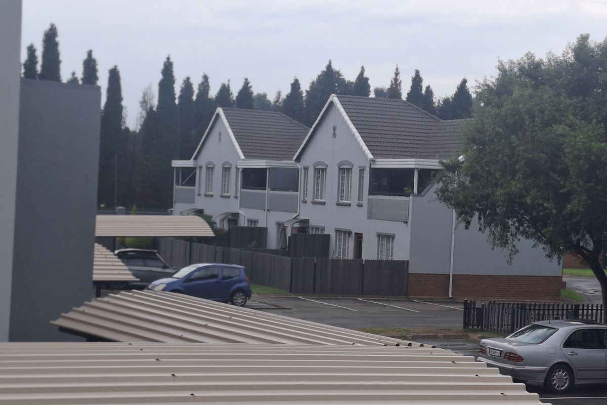 View of the apartment complex exterior, featuring gabled roof architecture, covered parking bays, and surrounding residential landscaping.