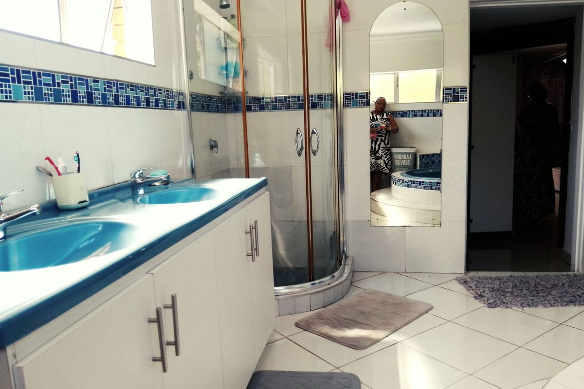 A functional bathroom featuring a double vanity, shower enclosure, and tiled finishes with a classic blue and white aesthetic.